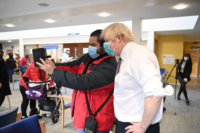 Prime Minister Boris Johnson takes a selfie with a member of the public during a visit to Lordship Lane Primary care Centre in north London to meet staff and see people receiving their booster vaccines. (PA)