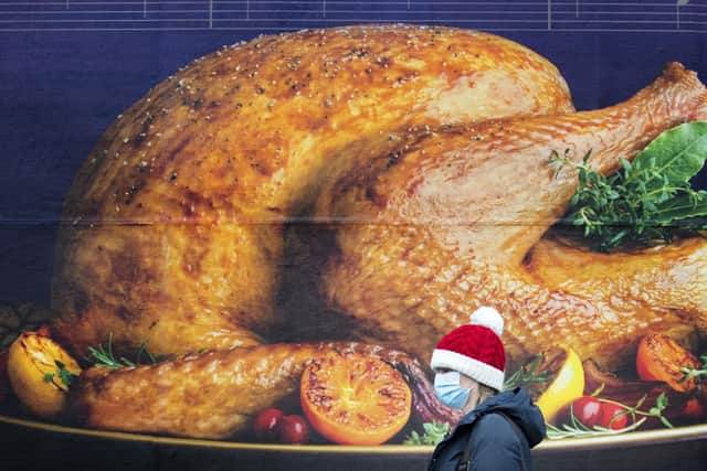A shopper, wearing a Santa hat, passing a billboard poster featuring a Christmas turkey