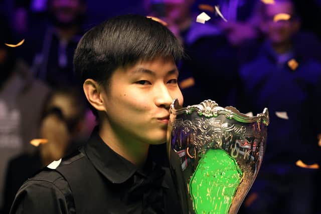 Zhao Xintong kisses the trophy.