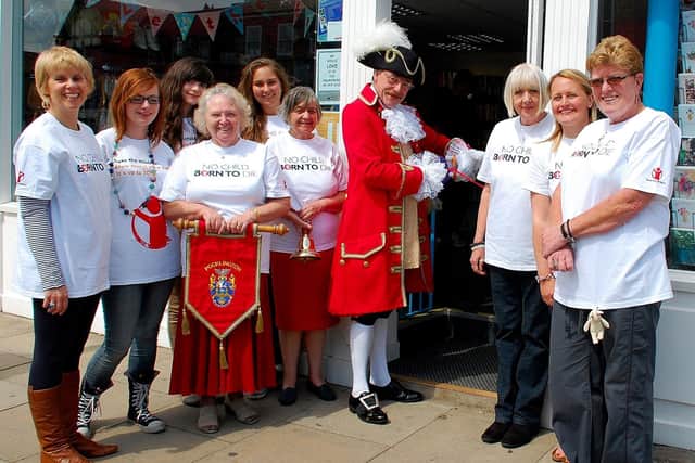 This image shows members of staff and town crier Geoff Sheasby when the Save the Children shop opened. Photo courtesy of Roger Pattison