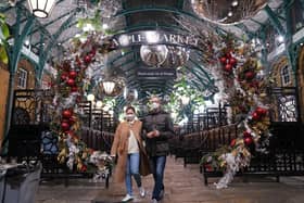 People walking underneath decorations in the Covent Garden Christmas market, London.