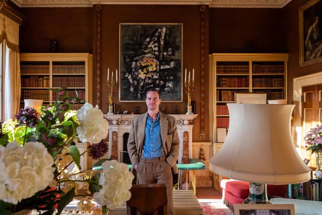 Robert Sheffield in the library where an old portrait over the fireplace was swapped for an abstract painting by Frank Avray Wilson.