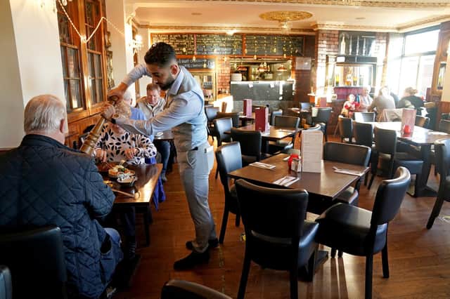 A waiter carries meals to some of the few customers dining at Cassia Sambuca restaurant in North Shields, North Tyneside, which would normally be packed with customers taking advantage of lunchtime specials