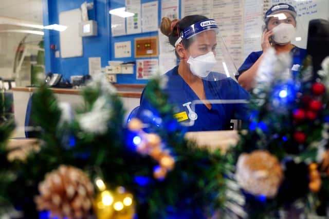 Nurses work at a desk surrounded by Christmas decorations on a ward for Covid patients.