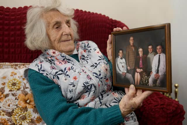 Olive Robinson with a photograph of her late husband and three sons, two of whom have predeceased her