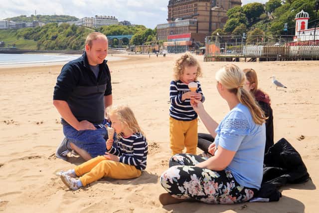 A family enjoy an ice-cream together on the beach in Scarborough - one of Yorkshire's most popular tourist destinations.