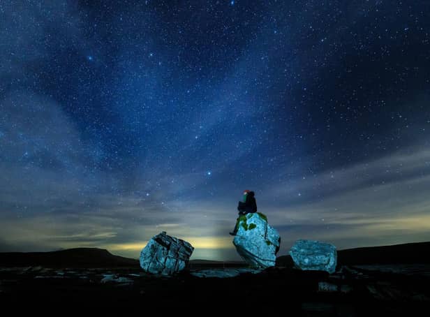 A walker looks up into the night sky above Twistleton Scar in The Yorkshire Dales National Park