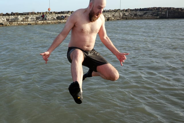 Nathan McCall leaps into Carnlough harbour during the New Year's Day charity swim.  Picture: Stephen Davison / Pacemaker.