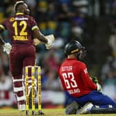 FIRST DOWN: England's captain Jos Buttler sinks to his kneels as West Indies' all-rounder Andre Russell scores runs during the first T20 cricket match at Kensington Oval in Bridgetown, Barbados. Picture: AP/Ricardo Mazalan