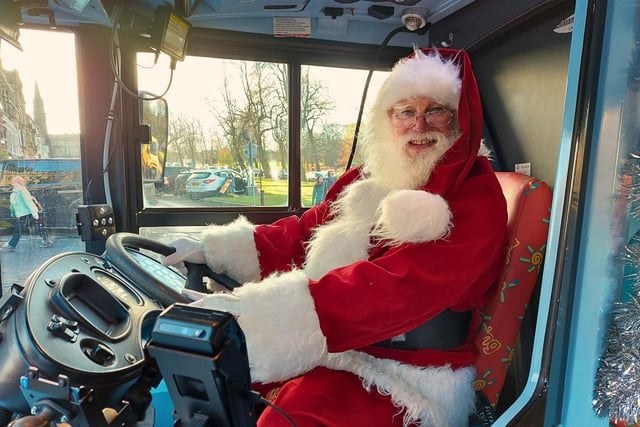 Santa in front of the wheel on the bus.