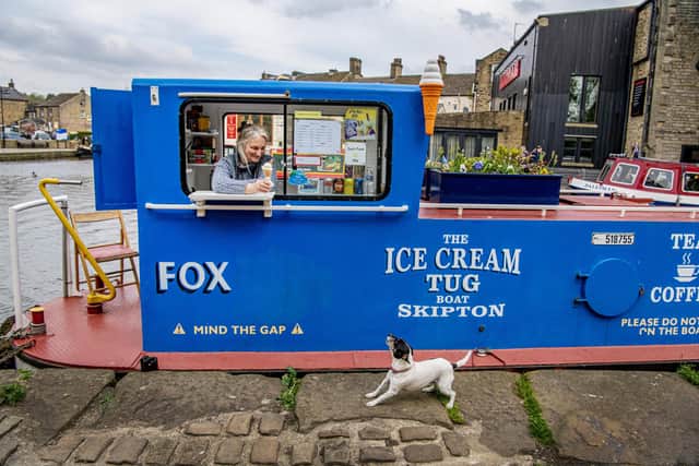 Caroline Hewes with her dog Roo on the Ice Cream Tug Boat moored in Skipton photographed for The Yorkshire Post by Tony Johnson. This is the tenth year of trading on the boat in the North Yorkshire town.   4th May 2023