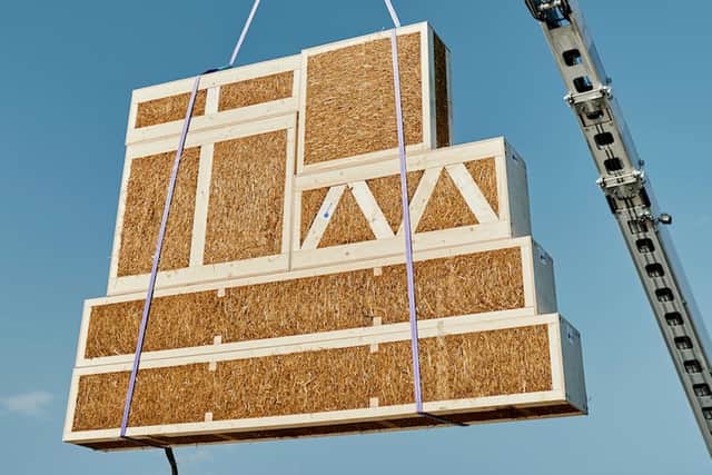 A straw bale panel being hoisted into place on a build