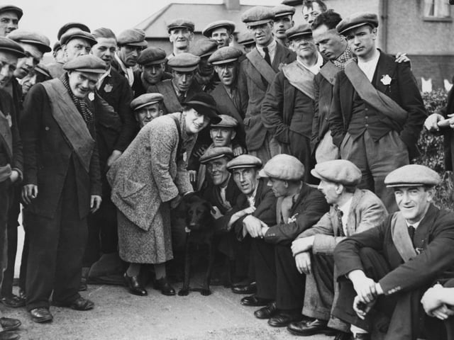 Labour MP Ellen Wilkinson with the Jarrow marchers, and their black labrador mascot, at Harrogate during their march from Tyne and Wear to London in October 1936.