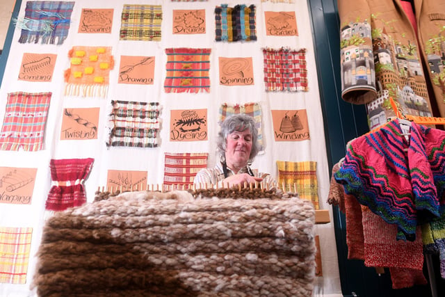 Edna Barker weaving a rug on a Peg loom with her works of art in the background.