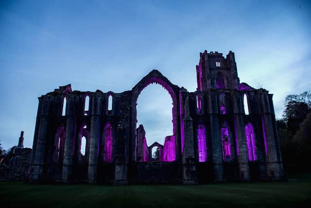 Fountains Abbey is lit in purple to celebrate the coronation of King Charles III ©National Trust_J Shepherd