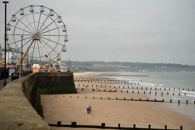 People walk along an empty beach in Bridlington. (Pic credit: Oli Scarff / AFP via Getty Images)