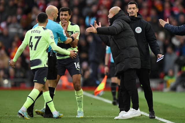 Manchester City's Spanish manager Pep Guardiola (2nd R) and his players surround English referee Anthony Taylor as he goes to the screen to look at a VAR (Video Assistant Referee) review ahead of his disallowing Foden's goal during the English Premier League football match between Liverpool and Manchester City at Anfield in Liverpool, north west England on October 16, 2022. (Photo by OLI SCARFF/AFP via Getty Images)