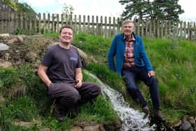 Jamie McEwan and Mark Corner by the water as it rejoins Backstone Gill after having gone through the new hydropower turbine.