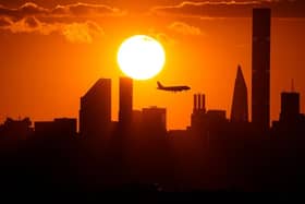 A plane flies over the New York City skyline at sunset. (Pic credit: Timothy A Clary / AFP via Getty Images)