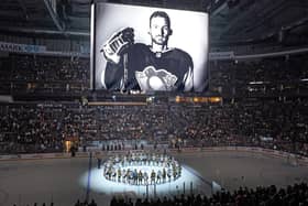 The Pittsburgh Penguins and Anaheim Ducks gather at center ice, before an NHL hockey game in Pittsburgh, Monday, Oct. 30, 2023, to honor former Penguin player Adam Johnson, shown on scoreboard, who died in while playing in an English hockey league game. (AP Photo/Gene J. Puskar)