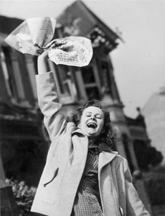 Mrs Pat Burgess of Palmers Green, North London waves a newspaper containing the news of Germany's surrender in World War II (Photo: Reg Speller/Fox Photos/Hulton Archive/Getty Images)
