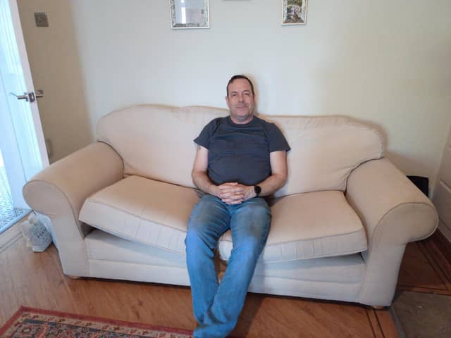 Darren Leeming, 54, sits on a couch he got for free from Facebook Marketplace.