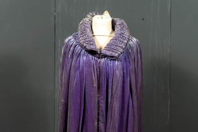 Lot 2046: Early 20th century blue velvet cape with stylised smocked collar and drop waistband, large single button fastening here, silver lame patterned lining. Estimate: £150-250 plus buyer’s premium