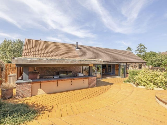 A wood-fired pizza oven, tiled worktops and Belfast sink create a dedicated space for preparing food outside.
