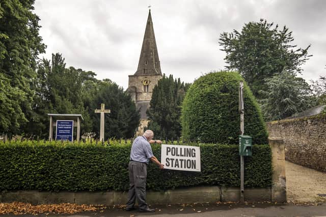 A man adjusts a polling station sign at Saint Martin Church in Womersley during a by-election in 2023. PIC: Danny Lawson/PA Wire