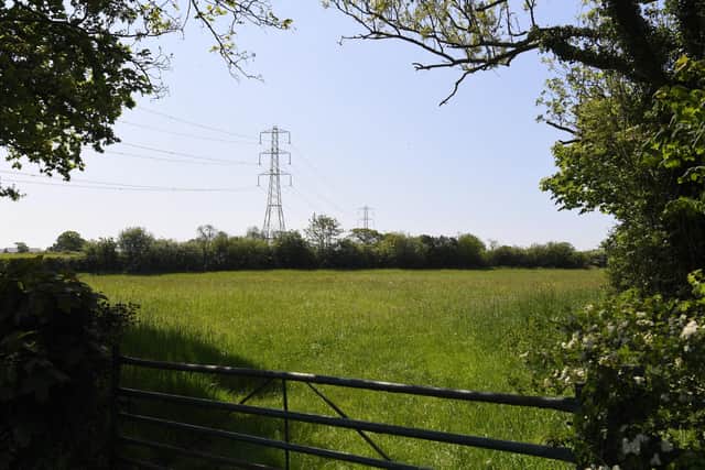 'What is the difference in the rural landscape between towering wind turbines and pylons?'