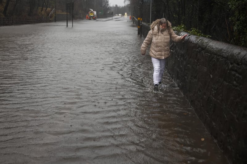 A woman walks through flooding on the A82 on December 27, 2023 in Dumbarton
