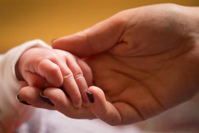 A mother holds the hand of a new-born baby. PIC: Dominic Lipinski/PA Wire
