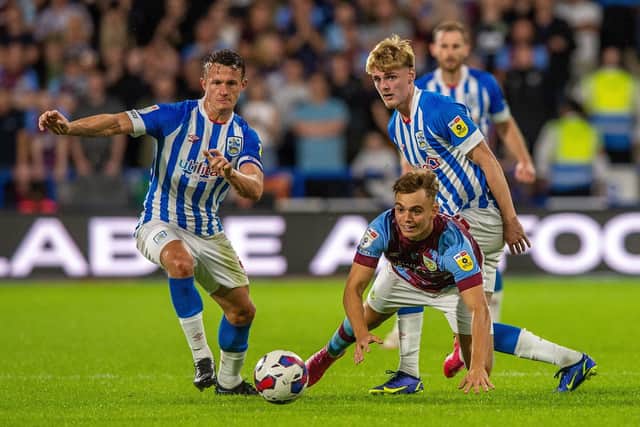 Burnley's Dwight McNeil falls under pressure from Huddersfield Town's Jonathan Hogg and Jack Rudoni.
 Huddersfield Town v Burnley FC.  SkyBet Championship.  John Smiths Stadium.
29 July 2023.  Picture Bruce Rollinson
