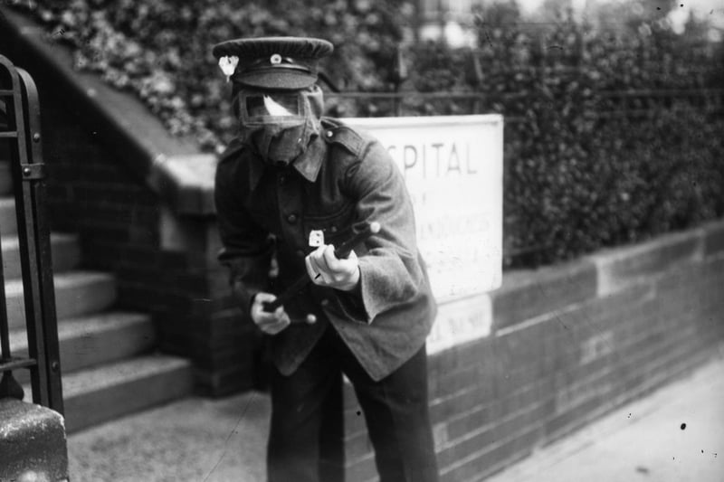 A soldier with a primitive gas mask brandishes a cane as a gun while on guard outside a hospital, Harrogate in July 1915.