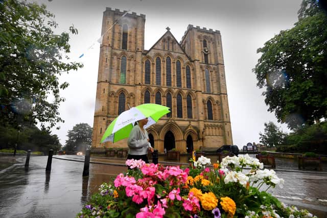A girl with an umbrella walks through the rain at Ripon Cathedral. PIC: Simon Hulme