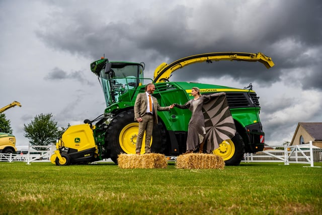 Great Yorkshire Show models Luke Johnson, and Lizzie McLaughlin wearing clothes as part of the Sheep to Chic Fashion Show sponsored by Brook Taverner in front of the latest examples of farming technology a John Deere 9700 Forage Harvester with it's innovative 30R grass pick-up, provided by Ripon Farm Services