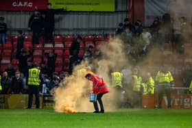 A steward removes a pyrotechnic thrown onto the playing surface at Gresty Road from the Bradford City section of the ground. Picture: Tony Johnson.