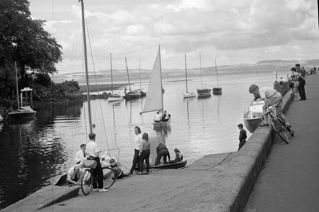 A yachtsman guides his craft down river past the old white houses at Cramond in July 1964.