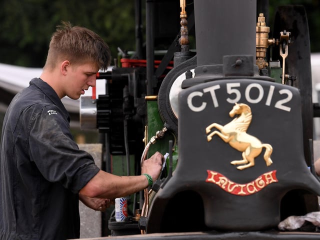 A young exhibitor gives one of the rally's impressive steam engines some careful attention