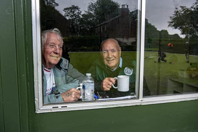 Maurice Sykes and Maurice Holleran peer out of the club house at Harehills Crown Green Bowling club in Leeds playing a league match with Moor Allerton in the pouring rain, photographed for the Yorkshire Post by Tony Johnson.