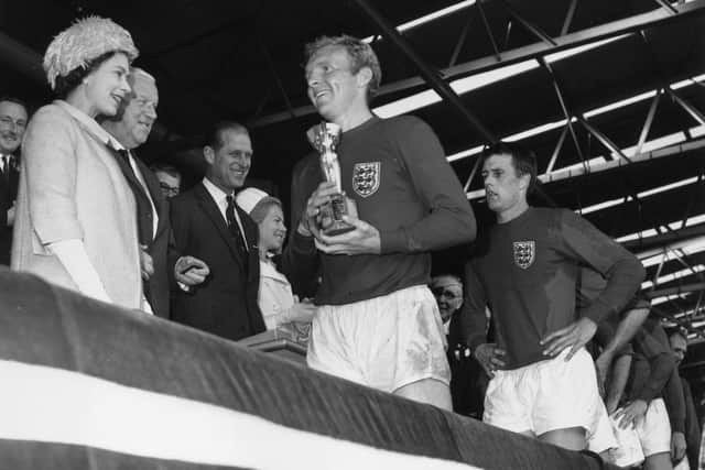 Queen Elizabeth II smiles after presenting England captain Bobby Moore with the Jules Rimet trophy, following England's 4-2 victory over West Germany in the World Cup Final at Wembley Stadium, 1966. Photo by Keystone/Getty Images.