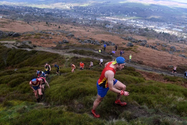 A long line of runners tackling the steep hill of the moor.