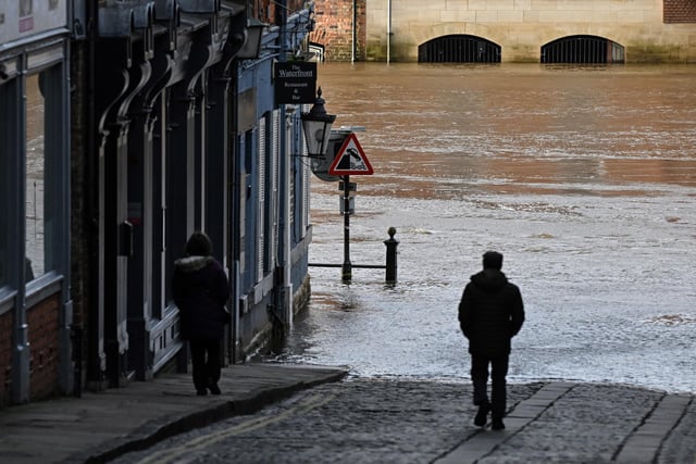 A man walks down a lane facing a street flooded by the River Ouse after it burst its banks, in central York.