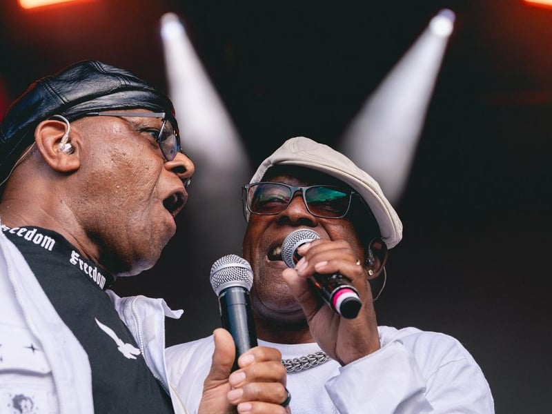 Original members of The Real Thing Chris Amoo and Dave Smith singing on stage.