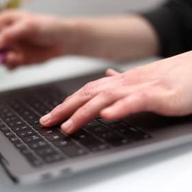 A woman using a laptop as she holds a bank card. PIC: Tim Goode/PA Wire