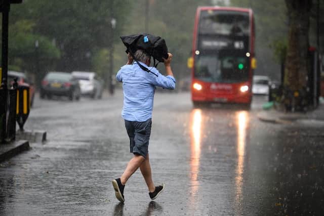 A man uses a bag for shelter as he crosses the road. (Pic credit: Leon Neal / Getty Images)