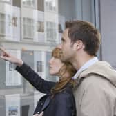 Side view of a young couple looking at window display at real estate office