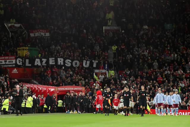 MANCHESTER, ENGLAND - NOVEMBER 10: Players of both teams  walk out to pitch as fans display banners reading "Glazers Out" during the Carabao Cup Third Round match between Manchester United and Aston Villa at Old Trafford on November 10, 2022 in Manchester, England. (Photo by Lewis Storey/Getty Images)