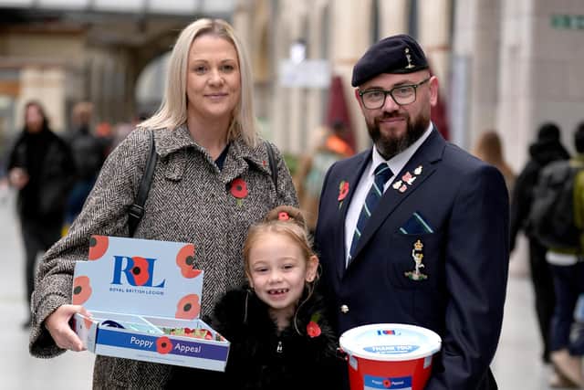 Ivy Knighton-Leake, 6, one of the UK's youngest collectors, holds one of four special poppies presented to her during the Royal British Legion Poppy Appeal 2026 national launch at Manchester Victoria Station, as she stands with her parents, Kimberley Leake and Steven Knighton.