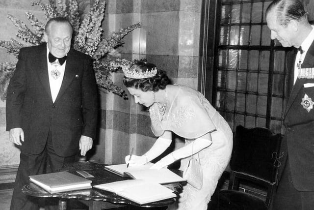 The Queen, watched by Prince Philip and the Lord Mayor of Leeds, Councillor William Hudson, signs the visitor's book at Leeds Civic Hall in July 1977.